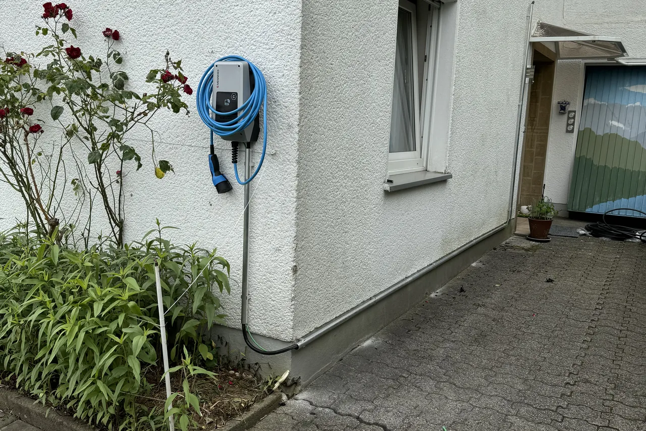 Wallbox mit blauem Ladekabel an einer Außenwand