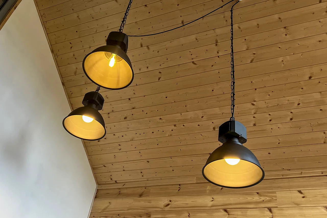 Drei warme Pendelleuchten unter einer Holzdecke